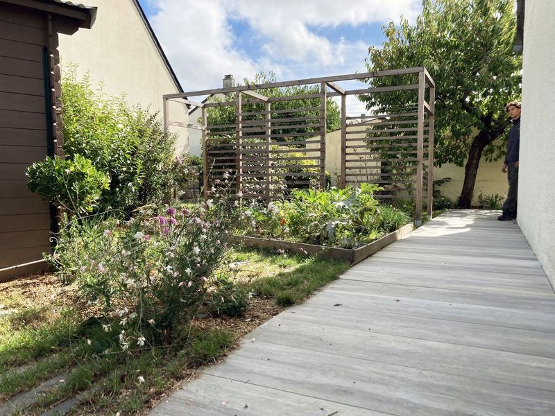 Terrasse, arche bois et massifs fleuris du Cocon Nourricier, Angers
