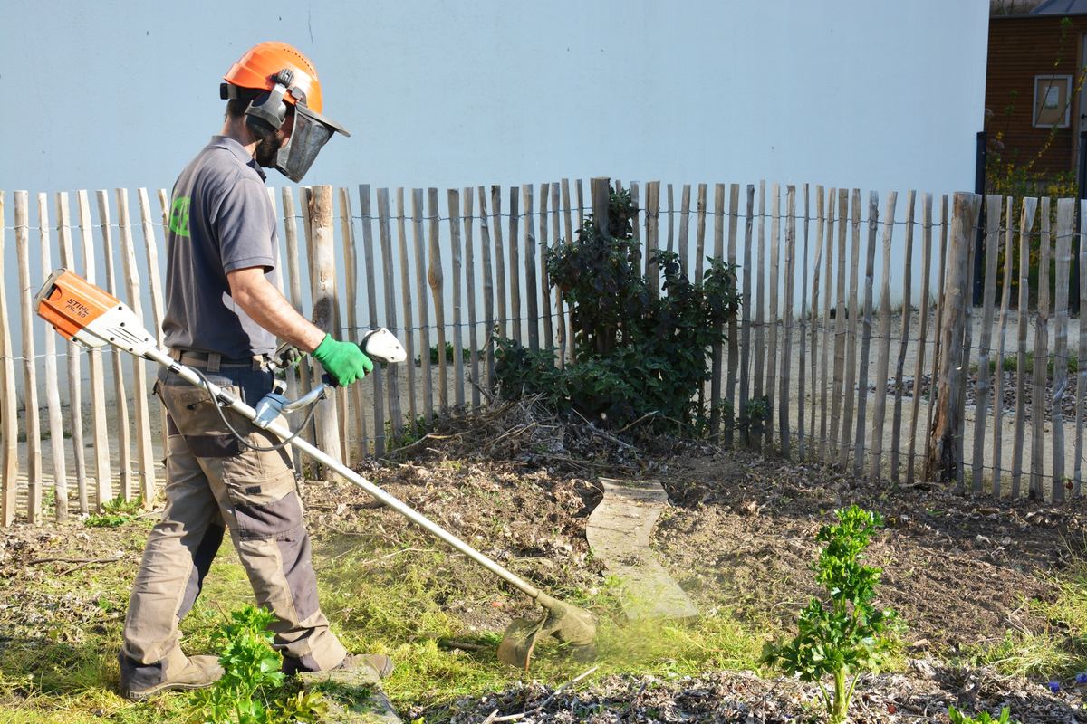 Jardinier SICLE en débroussaillage devant une clôture de ganivelles